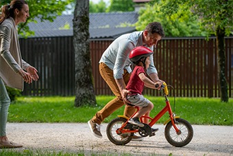 father pushing child on bike