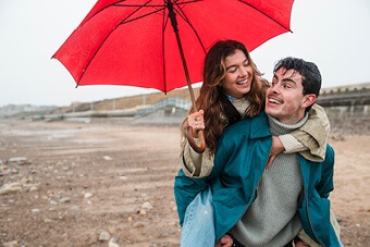 couple on the beach with a red umbrella 