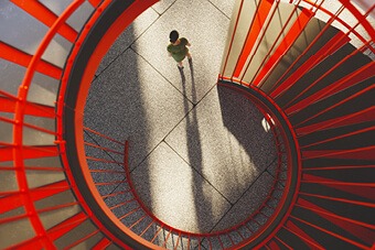 Person at the bottom of a red spiral staircase