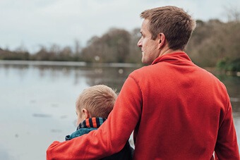Father and son standing next to a lake