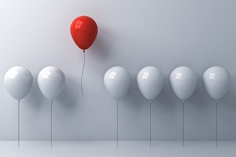 Row of white balloons with a red balloon floating above them