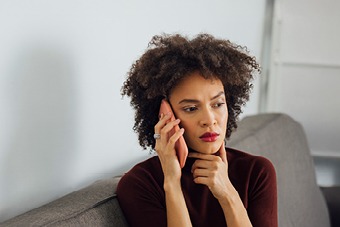 Woman sat on a sofa taking a phone call