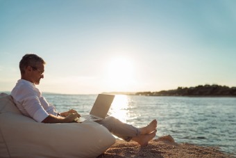 Man relaxing on beach with laptop