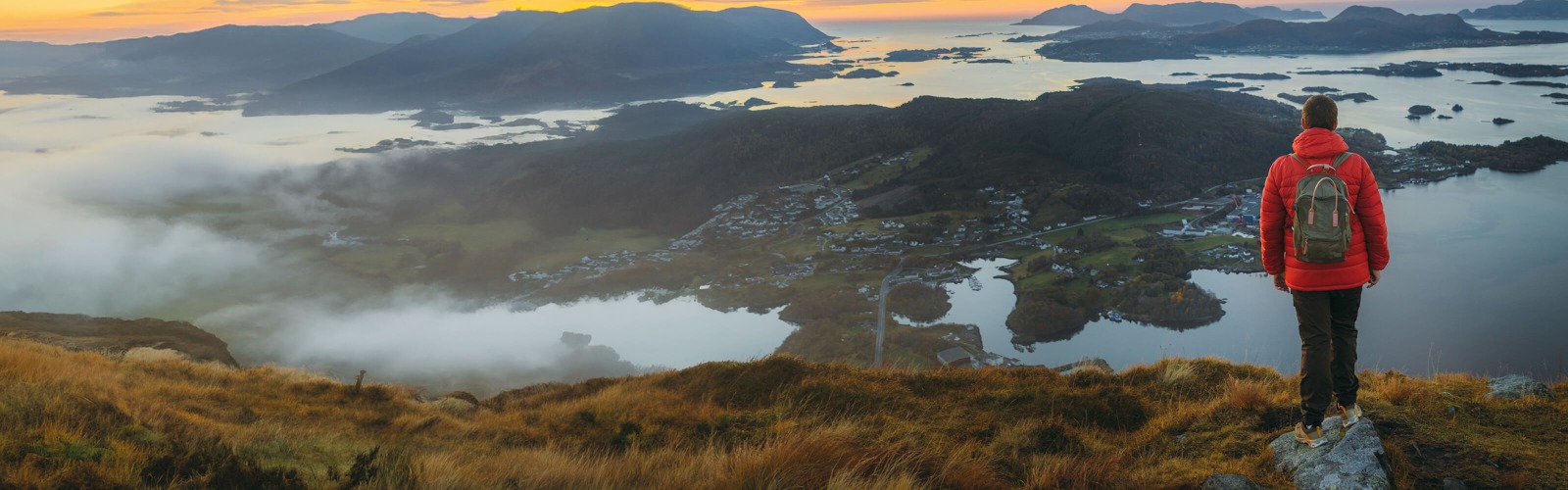 Man in a red jacket looking our from a mountain