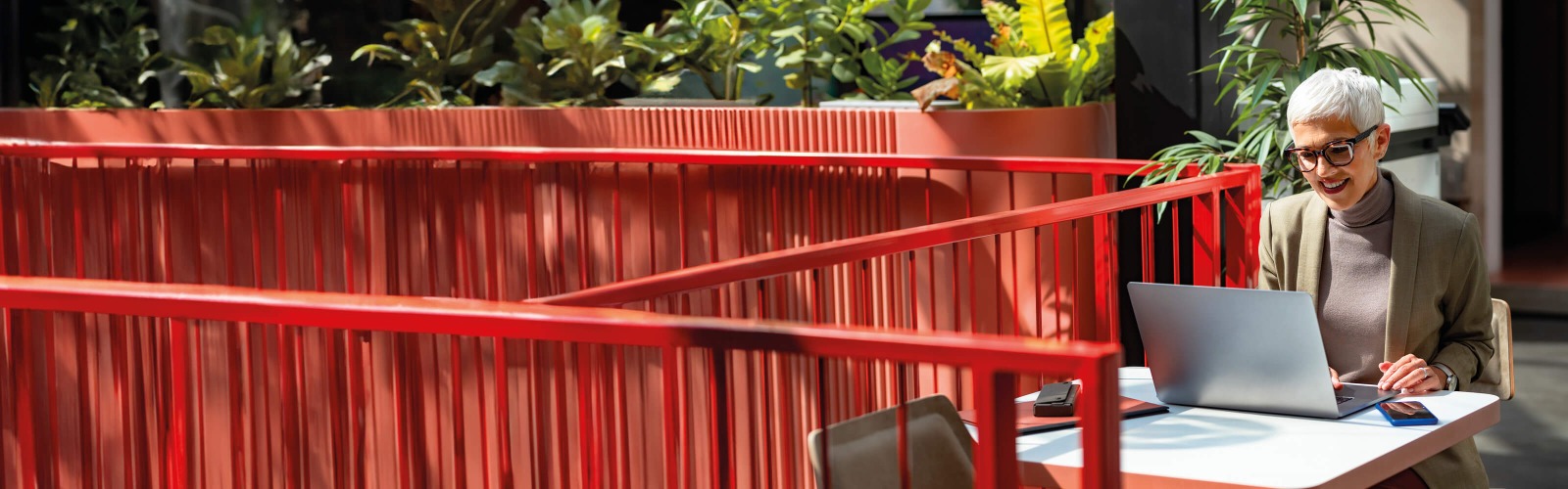 Woman on laptop next to red fence