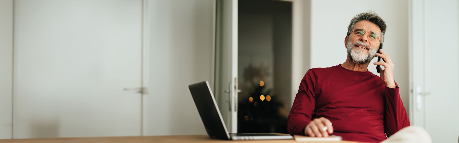 Man in red jumper sat next to a laptop
