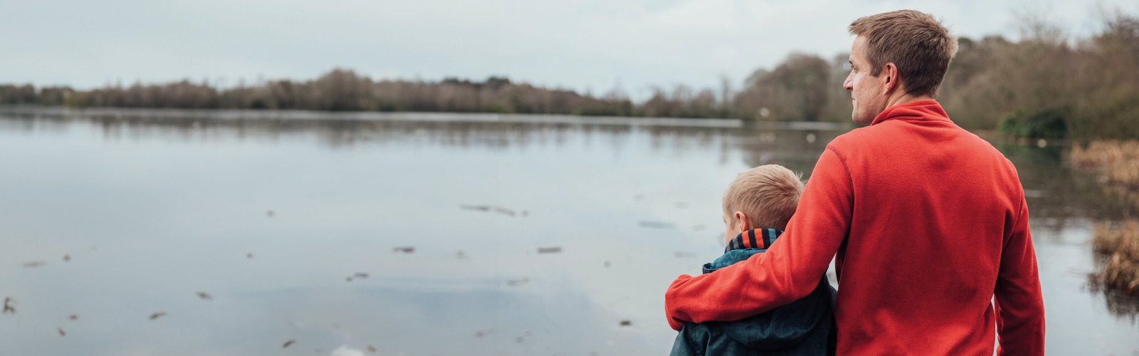 Father and son standing next to a lake