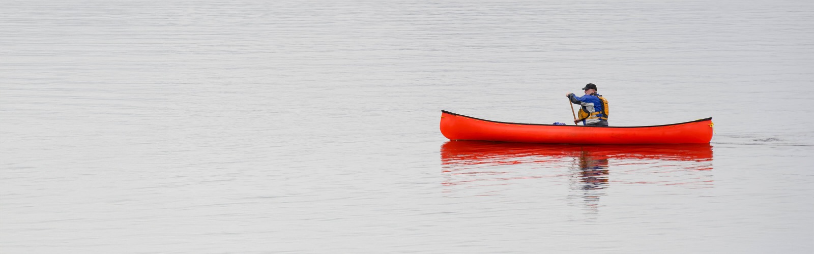 man in a red canoe on a body of water