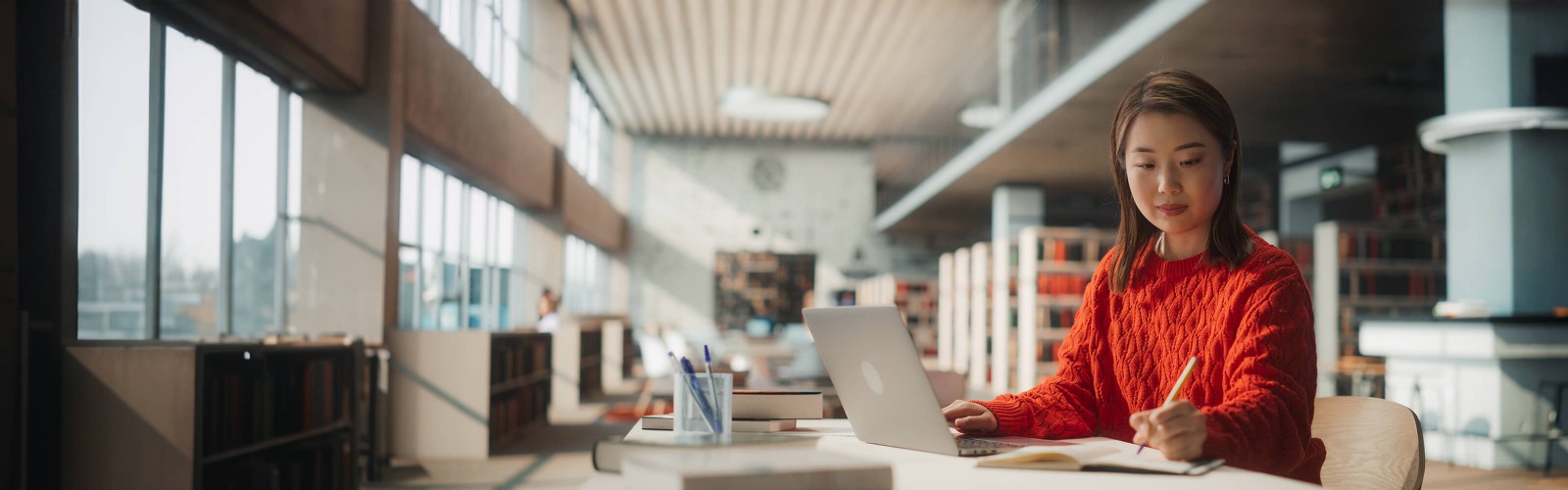 Woman on desk with laptop, writing