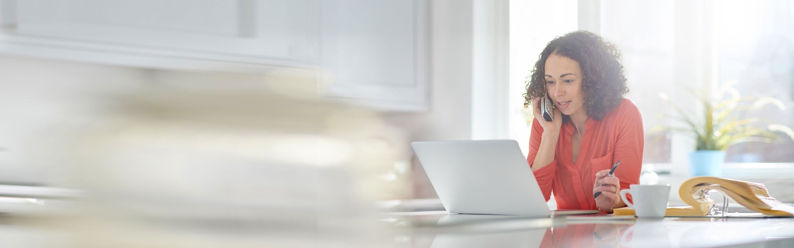 Woman on the phone sat down next to her laptop
