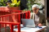 Woman on laptop next to red fence