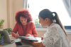 two women looking at papers
